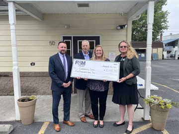 representatives pictured holding large check Community Cares