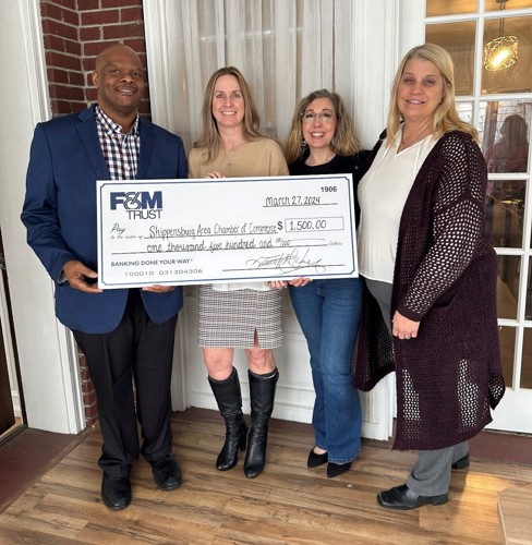 Two F&M Trust employees presenting a large check to two members of the Shippensburg Area Chamber of Commerce.