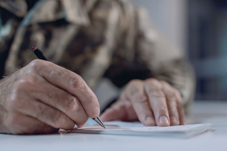 Image of an older man in a military uniform signing papers.