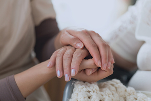 Image of an older woman and a younger woman holding hands.